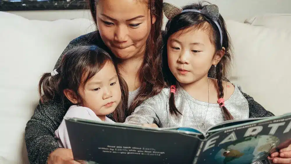A mother reading to her two daughters.