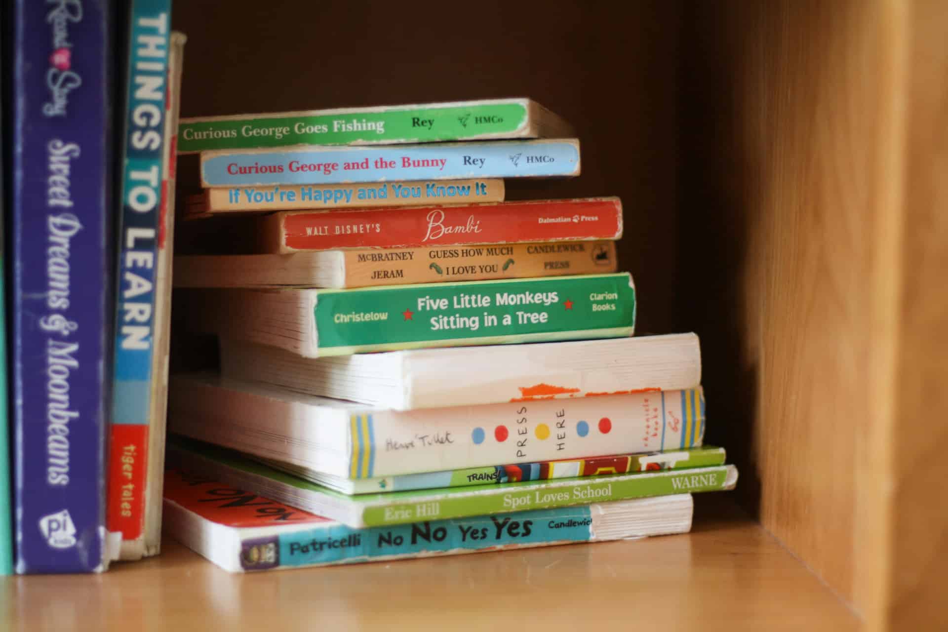 stack of children's books on a wooden bookshelf